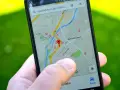 Palec wskazuje na mapę GPS w telefonie, szukając apteki w pobliżu. W samochodzie taka nawigacja to podstawa.