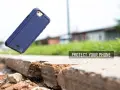 Granatowe etui na telefon spada na ziemię, pokazując jego ochronne właściwości.