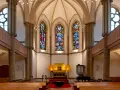 Festlicher evangelischer Gottesdienst am Heiligabend in einer Kirche mit Buntglasfenstern und Holzbänken.