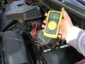 Sprawdzanie akumulatora w Renault Master. Multimetr pokazuje 12.13V.
