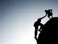 Silhouette d'un grimpeur aidant un autre à atteindre le sommet. Une belle présentation photographe de l'entraide et de la persévérance.