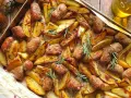 Salsiccia e patate al forno, dorate e profumate al rosmarino, pronte per essere gustate.