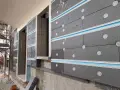 Pannelli grigi per cappotto termico ignifugo, fissati con tasselli bianchi e profili azzurri, in fase di installazione su un edificio.