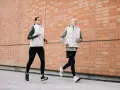 Coppia corre lungo un muro di mattoni. Ottimi consigli per correre in coppia, con abbigliamento tecnico.