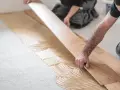 Handwerker verlegen sorgfältig Parkett auf Kleber. Die Holzbretter werden präzise nebeneinander gelegt, um ein schönes Ergebnis zu erzielen.