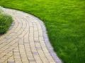 Vialetti giardino fai da te in pietra, con prato verde curato e aiuole fiorite.