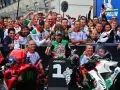 El equipo celebra un podio en el calendario MotoGP. El piloto número 1, rodeado de su equipo, muestra su alegría.