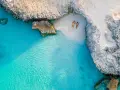 Para na plaży na wyspie Aruba, otoczeni turkusową wodą i skalistymi klifami. Idealne miejsce na relaks.