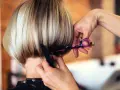 Fryzjerka modeluje cieniowany bob do ramion, używając nożyczek i grzebienia.