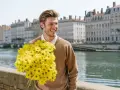 Hombre sonriente con un gran ramo de flores amarillas, quizás buscando el significado de flores para hombres.