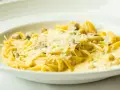 Pyszny makaron z grzybami w kremowym sosie, posypany parmezanem. Idealny przepis na obiad.