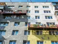 Remont bloku mieszkalnego w toku. Czy remont mieszkania trzeba zgłaszać? Pracownicy na rusztowaniach ocieplają budynek.