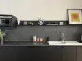 Encimera de cocina negra con vetas blancas, lista para cambiar. Microondas, fregadero y decoración moderna.