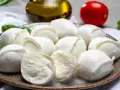 Frische Mozzarellakugeln auf einem Teller, garniert mit Basilikum. Perfekt für eine leichte Mahlzeit während der Schwangerschaft.