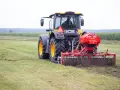 Ciągnik JCB z rozsiewaczem nawozu na polu.