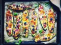 Zucchini-Hälften mit Käse, Oliven, Zwiebeln und Salami, die wie Pizza belegt sind. Sie schmeckt zucchini auf pizza!