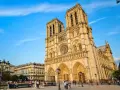 La majestueuse façade de Notre Dame de Paris se dresse sous un ciel bleu, ornée de détails gothiques. Des passants flânent sur la place.
