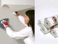 Kvinna med handskar sätter upp renoveringstapet på strukturtapet. Rullar med tapet syns också.