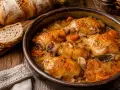 Muslos de pollo en salsa, una receta de la abuela que huele a hogar. Acompañados de pan rústico y zanahorias tiernas.