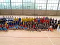 Drużyna Olimp Grodków na hali sportowej. Duża grupa dzieci i młodzieży w strojach sportowych pozuje do wspólnego zdjęcia.