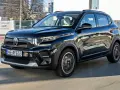 Czarny Citroen C3 porusza się po mieście, odbijając światła i budynki w swojej lśniącej karoserii.