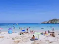 Słoneczna plaża na Majorce, pełna ludzi kąpiących się i opalających. Idealne majorka atrakcje dla dzieci i dorosłych.