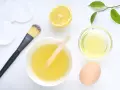 Ingredientes para una mascarilla casera para el pelo: limón, huevo, aceite y aplicador.