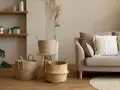 Przytulny salon w stylu boho: plecione kosze, beżowa kanapa z makramową poduszką i suszone trawy.