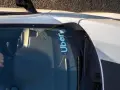 Fahrer hält das Lenkrad eines Autos mit Uber-Aufkleber auf der Windschutzscheibe.