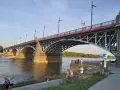 Most Poniatowskiego nad Wisłą, z ludźmi spacerującymi po bulwarach i podziwiającymi architekturę.