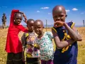 Dzieci z plemienia Masajów, żyjących w Kenii i Tanzanii, pozują do zdjęcia na tle sawanny.