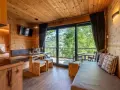 Przytulny domek z widokiem na góry, idealny na camping Seiser Alm. Drewniane wnętrze, wygodna kanapa i stół zapraszają do relaksu.