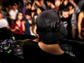 DJ aux platines, casque sur les oreilles, gérant le niveau sonore pour une foule en délire.