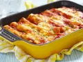 Pyszne cannelloni z mięsem mielonym, zapieczone pod sosem pomidorowym i serem, w żółtym naczyniu.