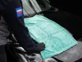 Person i handskar lägger en turkos mikrofiberduk på en svart bilhuv. Duken är från the rag company.