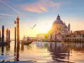 Gondola che scivola sull'acqua al tramonto, con la Basilica di Santa Maria della Salute sullo sfondo. Un'indimenticabile attività a Venezia.
