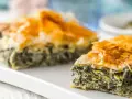 Chrupiąca spanakopita z warstwami ciasta filo i zielonym nadzieniem ze szpinaku i sera.