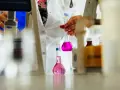 Ręce w białym fartuchu trzymające kolby z różowym płynem w laboratorium.