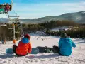 Dwaj snowboardziści odpoczywają na stoku, w tle widać wyciąg narciarski Karpacz i góry.