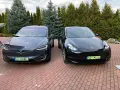 Dwa samochody Tesla, jeden ciemnoszary Model X, drugi czarny Model Y, stoją na podjeździe.