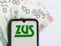 Telefon z logo ZUS na tle polskich banknotów. Oczekujesz zwrotu nadpłaty?