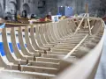 Struttura in legno di una barca veneziana in costruzione, con altre imbarcazioni sullo sfondo.