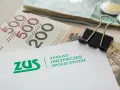 ZUS i pieniądze, symbolizujące rodzicielskie świadczenie uzupełniające.