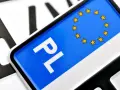 Zbliżenie na polskie tablice rejestracyjne z symbolem UE. Litery "PL" i gwiazdki na niebieskim tle.