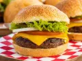 Soczysty burger z serem, sałatą, pomidorem i cebulą na czerwono-białej kratce.