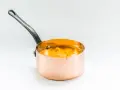 Cazo de cobre con puré de boniato cremoso y naranja, listo para servir.