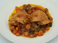 Dos piezas de pollo dorado sobre un guiso de verduras coloridas, zanahorias y berenjenas. Un delicioso pollo a la jardinera.