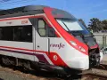 Czoło pociągu Renfe 225M z czerwonymi i białymi pasami, stojącego na torach.