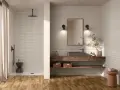 Aménagement salle de bain moderne avec douche à l'italienne, meuble vasque en bois flotté et sol en parquet.