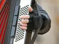 Dłoń w rękawiczce gra na akordeonie, wydobywając dźwięki tego wyjątkowego instrumentu.